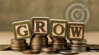 Wooden alphabet blocks spelling GROW placed on stacks of coins with target symbol, representing business growth and financial success concepts.