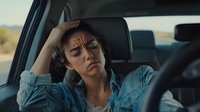 Stressed young Hispanic woman driver holding head in hand showing fatigue and frustration while sitting in car interior during road trip or commute.