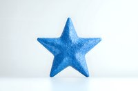 Blue textured star shape isolated on white background, decorative element with soft shadow reflection suitable for holiday designs and festive layouts.