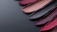 Colorful lipstick smears in pink, purple and burgundy shades on dark background. Cosmetic texture swatches for makeup and beauty product advertising.