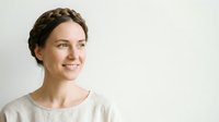 Young woman with braided hairstyle wearing casual beige shirt, smiling against white background. Portrait suitable for lifestyle, wellness, and professional applications.