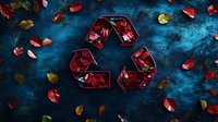 Red rose petals frozen in geometric ice cubes arranged in recycling symbol shape on dark blue textured background with scattered fresh petals and leaves.