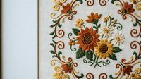 Embroidered sunflower pattern with decorative swirls on white fabric, traditional needlework design for home decor and textile crafts.