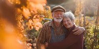 Happy senior Caucasian couple embracing in autumn vineyard during golden hour sunset, retirement lifestyle and love concept for advertising campaigns.