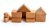 Wooden building blocks arranged in house shapes on white background, showcasing natural wood grain texture for children's educational play.
