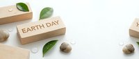 Wooden blocks with Earth Day text surrounded by green leaves and natural elements on white background for environmental awareness campaigns.