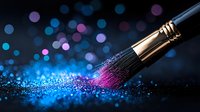 Makeup brush with pink powder explosion against dark background with blue and purple bokeh lights creating magical cosmetic art composition.