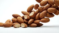 Whole and halved almonds scattered on white surface, showcasing nutty texture and natural color variation for food, nutrition, and culinary design projects.