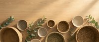 Natural woven baskets and ceramic bowls arranged with eucalyptus branches on wooden surface for home decor and organic lifestyle styling.