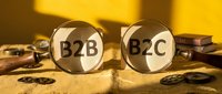 Two magnifying glasses displaying B2B and B2C text on sandy surface with coins and books, representing business models and market research for commerce strategies.
