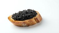 Slice of toasted bread topped with black caviar on white background, isolated food ingredient for culinary, gourmet, and restaurant design projects.