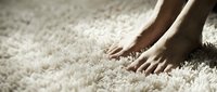 Bare feet touching soft white carpet texture, cozy home comfort and relaxation concept for interior design and flooring advertisements.