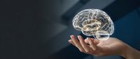Human hand holding glowing transparent brain hologram against dark background representing artificial intelligence, neuroscience and mental health concepts.