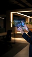 Businessman using futuristic holographic tablet displaying financial data charts and graphs in modern office with ambient lighting for business analytics.
