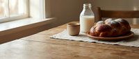 Fresh baked donuts on wooden plate with milk bottle and coffee cup on rustic kitchen table by sunny window for breakfast morning meal concept.