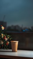 Cozy coffee cup with latte art on windowsill at dusk, alongside delicate roses and berries arrangement, creating peaceful morning atmosphere.