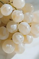 Fresh white grapes close-up macro shot showing translucent round berries with natural light and soft shadows, suitable for wine, food and harvest themes.