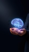 Businessman holding glowing holographic brain in cupped hands representing artificial intelligence, innovation and mental health concepts on dark background.