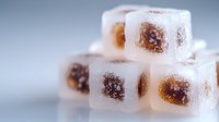 Turkish delight cubes dusted with powdered sugar in soft focus macro shot against blurred background, showing sweet texture and traditional confectionery details.