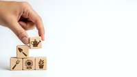 Hand placing wooden cube with watering can icon completing eco-friendly gardening symbol set on white background for sustainable agriculture concepts.