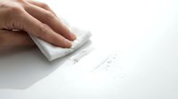Hand using white eraser to remove pencil marks from paper surface, mistake correction and editing concept for office and school supplies.