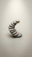 Balanced stack of smooth river stones creating curved tower on neutral background for zen meditation and wellness concepts.
