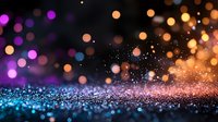 Magical glitter sparkles on dark background with blue, purple and golden bokeh lights creating dreamy festive atmosphere. Abstract defocused backdrop.