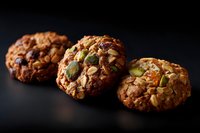 Freshly baked homemade cookies with pumpkin seeds, nuts and chocolate chips on dark background, close up view of artisanal bakery treats.