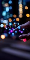 Finger touching digital network with glowing social media and technology icons floating against blurred city lights background, representing connectivity and IoT concept.
