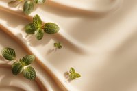 Fresh green mint leaves scattered on smooth beige silk fabric creating elegant natural composition with soft shadows and folds.