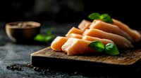 Fresh raw salmon fillet slices arranged on wooden cutting board with basil leaves and black pepper, dark moody background for restaurant menu.