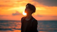 Young Asian woman silhouette against dramatic orange sunset sky over ocean, head tilted back in peaceful moment of reflection and freedom. Atmospheric beach scene.