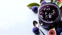 Homemade blueberry jam in glass jar with fresh berries and spoon on white surface, ready for breakfast or baking projects.