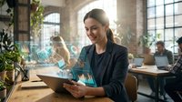 Young professional businesswoman analyzing holographic data charts and graphs on tablet in modern office workspace with natural lighting.