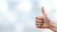 Hand showing thumbs up gesture against cloudy sky background expressing approval, success and positive feedback for business and motivation concepts.