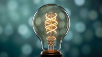 Vintage Edison bulb with glowing spiral filament against soft bokeh background. Retro lighting design element for creative projects and interior decor concepts.