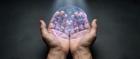Hands holding transparent sphere filled with colorful pills and capsules representing healthcare, medicine, pharmaceutical industry and treatment options.