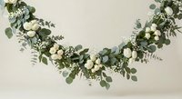 Elegant eucalyptus garland with white roses and baby's breath flowers arranged in graceful arch against neutral background for wedding decor.