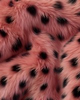 Luxurious pink faux fur texture with black spots pattern for fashion design and textile applications.