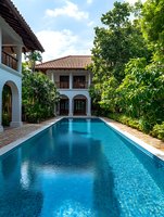 Luxury colonial style villa with swimming pool surrounded by lush tropical gardens and white architecture under blue sky for vacation resort concept.