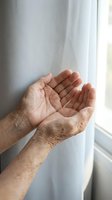 Elderly hands cupped together in prayer or receiving gesture by window with soft natural light creating peaceful spiritual moment for meditation concepts.