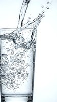 Clear water pouring into glass with dynamic splash and bubbles on white background for hydration and refreshment concepts.