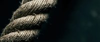 Thick natural jute rope with detailed fiber texture coiled in spiral pattern against dark background for nautical maritime and rustic design projects.