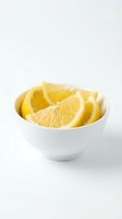 Fresh lemon wedges in white ceramic bowl on clean background for culinary and healthy lifestyle content.
