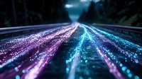 Glowing neon light trails on dark road with forest silhouettes, long exposure effect creates vibrant pink and blue streaks leading to vanishing point at night.
