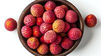 Fresh ripe lychee fruits in wooden bowl on white background, exotic tropical fruit with red rough skin and sweet juicy pulp, healthy organic produce.