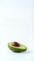 Fresh ripe avocado half with pit on clean white background isolated for healthy food design and culinary projects.