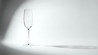Empty champagne flute glass on white background with soft shadow lighting for elegant dining and celebration concepts.
