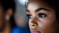 Young African American woman with natural makeup and defined eyebrows looking thoughtfully to the side in soft lighting for beauty and lifestyle concepts.