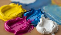 Vibrant acrylic paint colors yellow blue magenta white mixed on artist palette ready for creative artwork and painting projects.